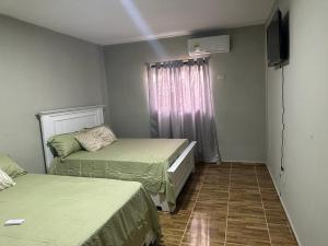 蒙特克里斯蒂省圣费尔南多Aparta Hotel Esa Buya的小房间设有两张床和电视