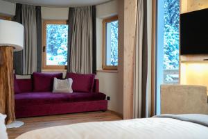 塞尔瓦迪加尔代纳山谷博匝玛尼格尼酒店的卧室在窗户前配有紫色沙发