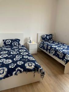 塞拉Appartement a la marina de salé的一间卧室配有两张带蓝白色床单的床