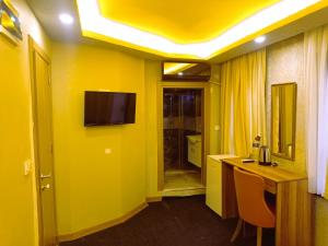 YıldırımGrand Marrakech Hotel的黄色的房间,设有一张桌子和墙上的一台电视机