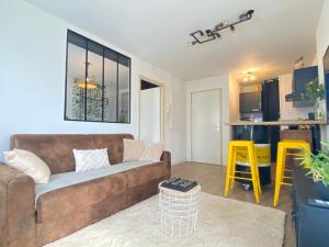 卢尔德L Escapade Lourdaise Balcon Parking Wifi ville的一间带棕色沙发的客厅和一间厨房