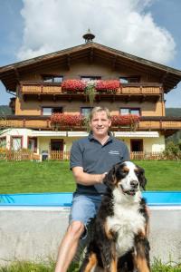 拉德施塔特兰德豪斯奥堡尔恩格特酒店的坐在狗旁边的房子前的人