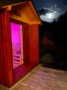 戈德马图杰克Alpine Wooden Villa with a View的一座带粉红色灯门的小木房子