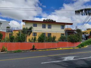 埃雷迪亚видовая квартира в Heredia的街道边的黄色和白色房子