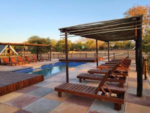 Dinokeng Game ReserveMzimkhulu Ranch & Resort的游泳池旁的一排木凳