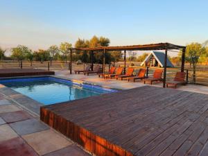 Dinokeng Game ReserveMzimkhulu Ranch & Resort的一个带长椅和木甲板的游泳池