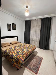 突尼斯Appartement L'aouina cité wahat的一间卧室配有一张带彩色毯子的床