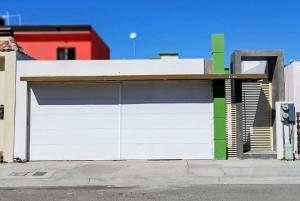 拉巴斯Casa Norte的车库设有白色和绿色的车库门