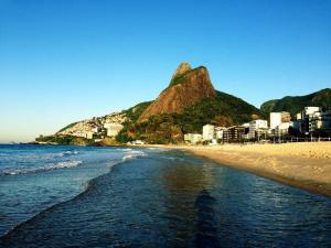 里约热内卢Lançamento,Duas suítes Leblon,segunda quadra da praia的享有海滩美景,背景为山脉