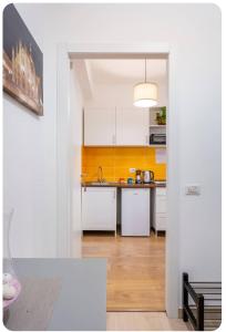 米兰Casa Rizzoli - bilocale vicinissimo M2的厨房配有白色橱柜和黄色墙壁