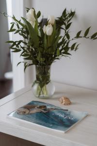 热那亚Il Giardino della Tartaruga的花瓶,有白色的花朵,桌子上有一个杂志
