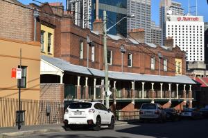 悉尼Discover The Rocks - Historical Terrace House的停在砖楼前的白色汽车