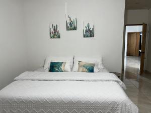 San CarlosPuerto San Carlos Bay House & Tours -1st Floor-的一张白色的床,墙上有三张照片