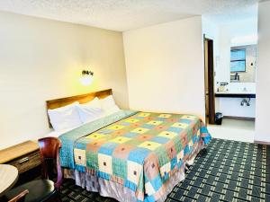 JayHoliday Pines Inn and Suites的酒店客房配有一张床铺和一张桌子。