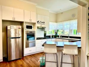 墨尔本Four Seasons Home家四季客栈的厨房配有白色橱柜和不锈钢冰箱