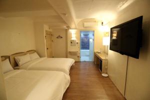 首尔Sinchon Gaon Hostel的酒店客房设有两张床和一台平面电视。