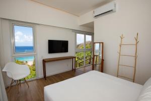 费尔南多 - 迪诺罗尼亚Pousada Mar em Mim的一间卧室设有一张床、一台电视和窗户。