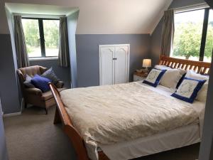 HunuaHunua Ranges的一间卧室配有一张床、一把椅子和窗户。
