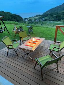 舞鹤市舞鶴ふるるファームコテージ的木制甲板配有椅子和一张带蜡烛的桌子
