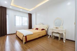 海防The Peninsula Haiphong的一间卧室配有一张床、一个梳妆台和镜子
