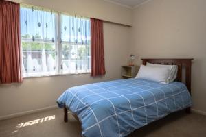 汉密尔顿Glenview home的一间卧室设有蓝色的床和2个窗户。