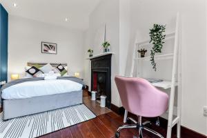 HanwellLovely 2-bedroom rental unit in Greater London的一间卧室配有一张床和一张粉红色的椅子
