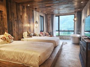 德清莫干·听山酒店的配有木墙和窗户的客房内的两张床