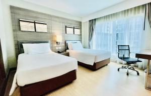曼谷Citrus Sukhumvit 11 by Compass Hospitality的酒店客房配有两张床和一张书桌