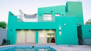 ChepesBambú Hotel的一座绿色房子,前面设有一个游泳池