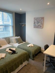 伦敦Comfy Private Bedrooms near Euston, Central London (127)的客房设有两张床、一张桌子和一张书桌。
