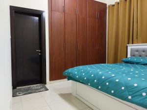 迪拜BEAUTIFUL VACATION HOME AT DUBAI BY MAUON TOURISM的一间卧室配有一张带蓝色床单和木制橱柜的床。