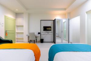 泗水Sans Hotel 88 Andalan Surabaya by RedDoorz的白色的客房配有两张床和一张书桌