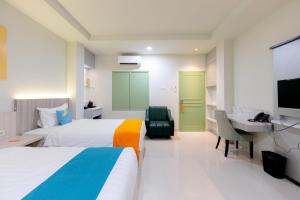 泗水Sans Hotel 88 Andalan Surabaya by RedDoorz的酒店客房设有两张床、一张桌子和一台电视。