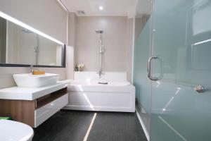 胡志明市Mother's Home的浴室配有白色浴缸、水槽和淋浴。