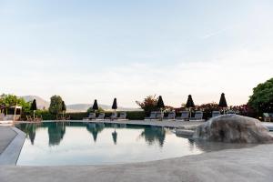 帕罗奇亚Paros Agnanti Resort & Spa的一个带椅子和岩石的度假村游泳池