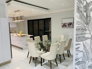 温特和克Essence Lifestyle Self-Catering Accommodation - Academia的用餐室以及带玻璃桌和白色椅子的厨房