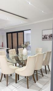 温特和克Essence Lifestyle Self-Catering Accommodation - Academia的一间设有玻璃桌和白色椅子的用餐室