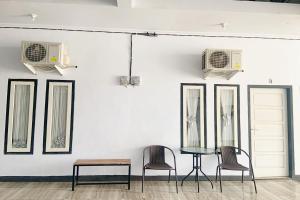 明古鲁省Pondokan Guest House Rinjani Syariah的墙上有三把椅子和一张桌子,墙上有镜子