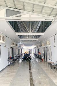 明古鲁省Pondokan Guest House Rinjani Syariah的摩托车停放在配有桌椅的大房间