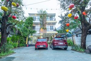 Tân Thành (1)Villa Hoi an-DimoVilla的两辆汽车停在一座带灯笼的建筑前