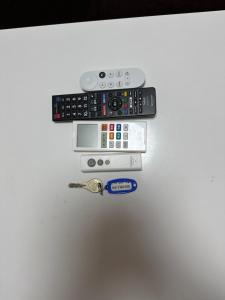 鹿儿岛短期賃貸ビッグバーンズマンション田上的两个遥控器和一个白色冰箱上的钥匙