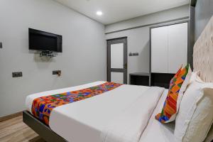 纳威孟买FabHotel Grand Inn I的卧室配有一张床,墙上配有电视。