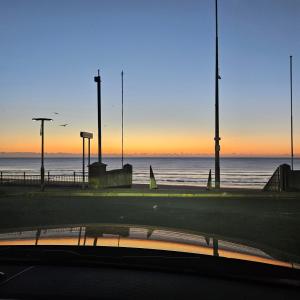 雷德卡Redcar Seaview Apartments的日落时分在汽车上欣赏海景