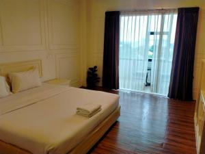 信武里府金龙度假酒店的一间卧室设有一张大床和一个大窗户