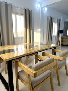 瓦加杜古Appartement - Le Grège的一张木桌、两把木椅和一张木桌,窗户上配有一张木桌