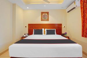 特里凡得琅Hotel Pallava Rajadhani的一间卧室配有一张大床和木制床头板