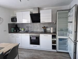 奥尔珀Ferienwohnung in Olpe-Rhode am Biggesee的厨房配有白色橱柜和冰箱。