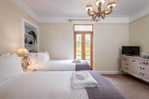 金斯巴恩斯Daisybank Kingsbarns - Beautiful 3 Bedroom Cottage的一间白色卧室,配有两张床和吊灯