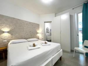 皮诺港Angolo Mare Apartments & Rooms的白色卧室配有一张大白色床和2条毛巾