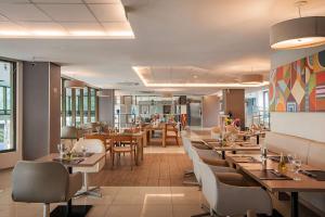 萨尔瓦多Wyndham Salvador Hangar Aeroporto的一间带木桌和椅子的餐厅和一间自助餐厅